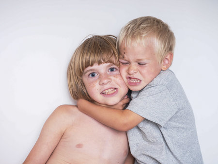 little boy and girl hugging each other on white background, studio shotの写真素材