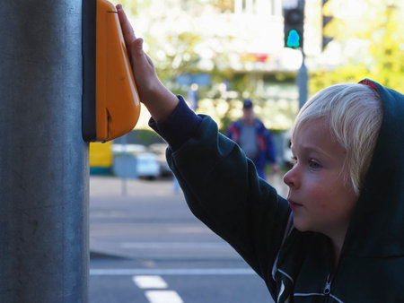 Cute little boy using a traffic light in a city street.の写真素材