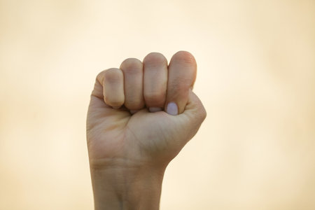 Close up of a fist in the air on a blurred background.の写真素材