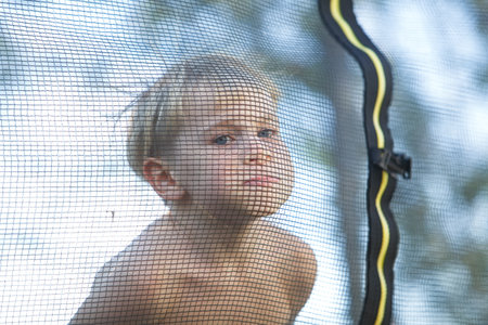 Cute little boy with static electricy hair, having his funny portrait taken outdoors on a trampolineの写真素材