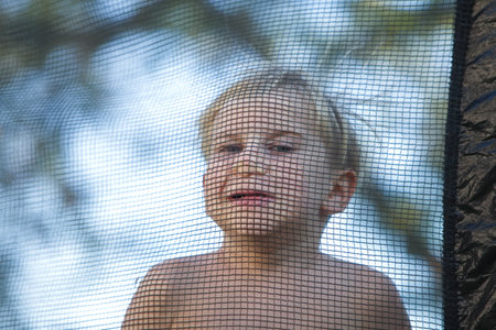 Cute little boy with static electricy hair, having his funny portrait taken outdoors on a trampolineの写真素材