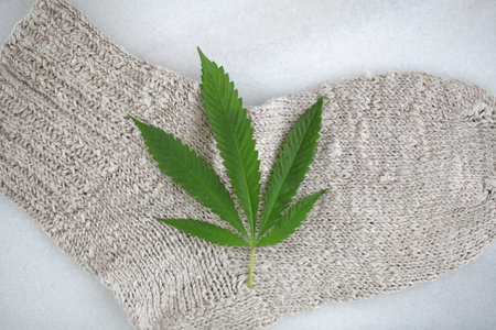 Cannabis leaf on a knitted scarf on a white backgroundの写真素材