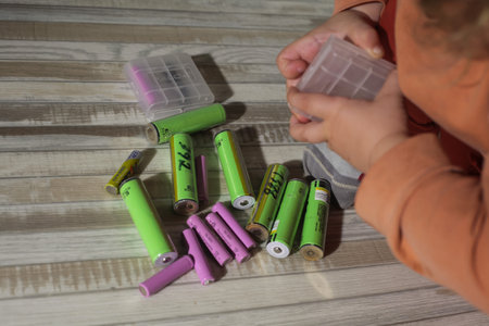 Batteries for recycling in the child's hands on a wooden background
