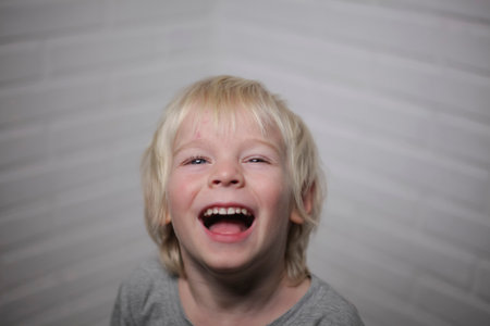 portrait of a little boy with blond hair and blue eyes laughingの写真素材