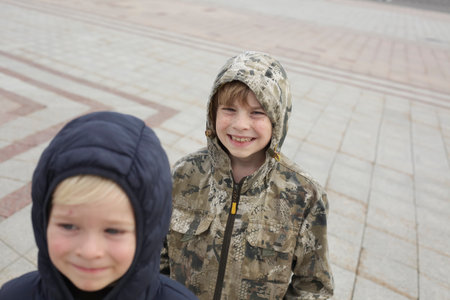 Portrait of two boys in camouflage jackets and hats on the streetの写真素材