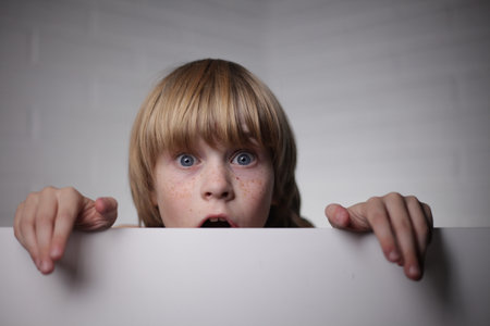 little girl with a blank sheet of paper in her hands and looks surprisedの写真素材