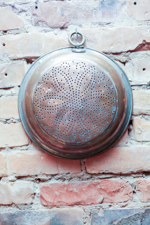 Vintage metal kitchen utensils on a brick wall background.