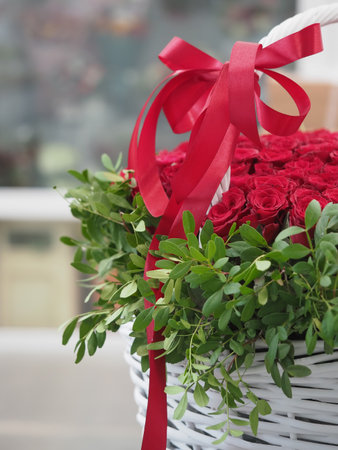 Bouquet of red roses in a basket with a red ribbonの写真素材