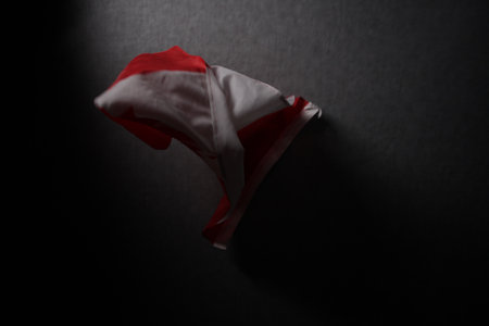 Crumpled red and white flag on black background with copy space