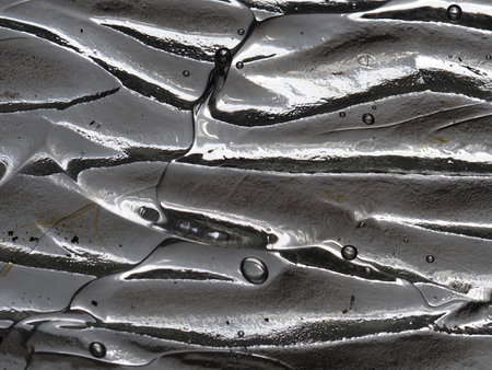abstract background of oil drops on a silver metal surface close upの写真素材