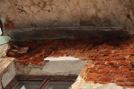 the facade of a brick house is cracked, the plaster is destroyed