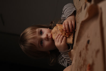 children two boys eating pizza at home sitting at the tableの写真素材