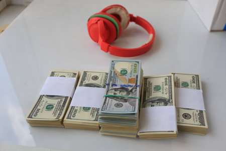 Dollars and headphones on a white table in the office.の写真素材