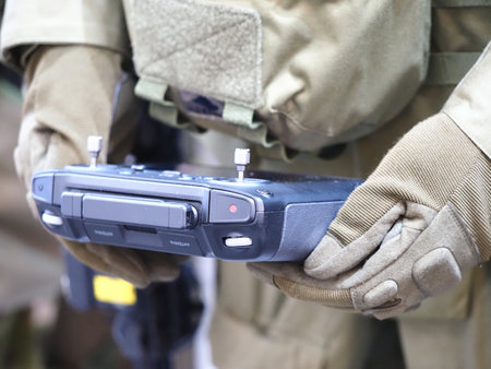 Close-up of a hand holding a remote control in a military uniform