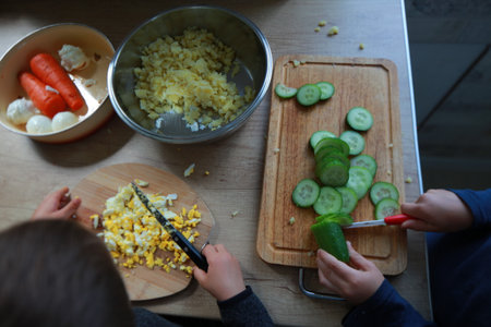 child's hands cutting vegetables for salad close upの写真素材