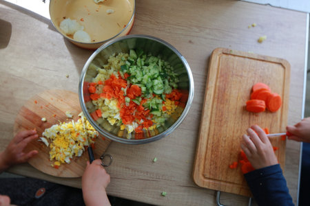 child's hands cutting vegetables for salad close up