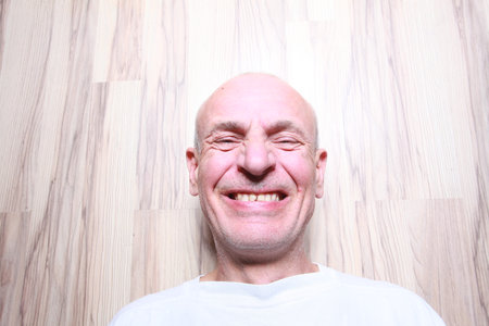 Portrait of a smiling senior man on a wooden background in the studioの写真素材