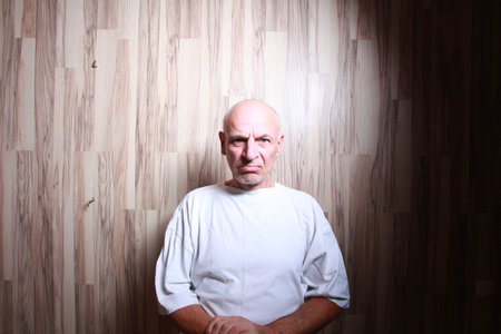 Portrait of a bald man with a white t-shirt on a wooden backgroundの写真素材