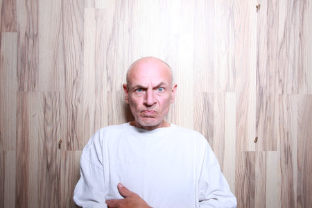 portrait of a bald man in a white T-shirt on a wooden backgroundの写真素材