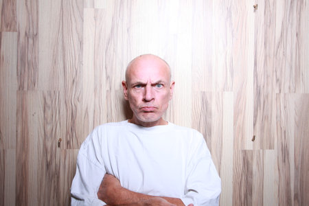Portrait of a bald man in a white T-shirt on a wooden backgroundの写真素材