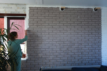 woman painting a wall with a roller and a brush in her handの写真素材