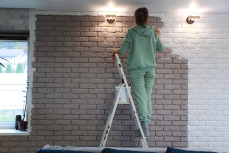 Young woman painting a wall in her new apartment. House renovationの写真素材
