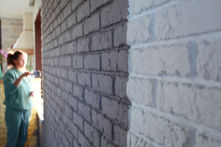 Worker plastering brick wall with putty knife and spatulaの写真素材