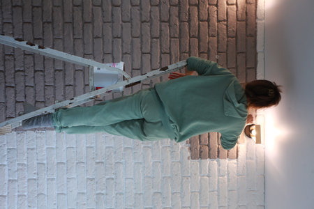 Young woman with a tool in her hand repairs a brick wall.の写真素材