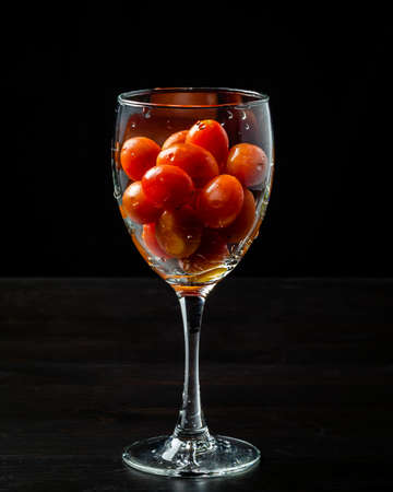 Fresh grape tomatoes in a glass. Tomatoes. Cherry tomatoes. Cocktail tomatoes. Black background.の写真素材