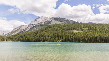 Forest reflect on the surface of Johnson Lake cloudy day - Banff National Park, Alberta, Canadaの写真素材