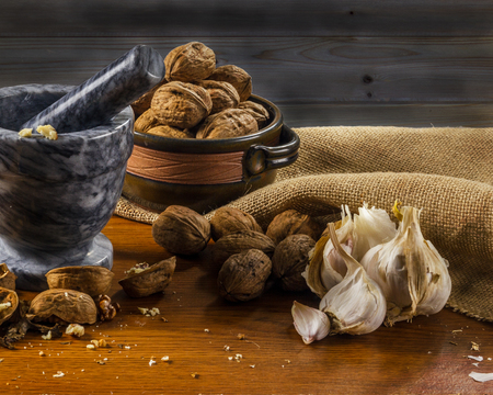 Mortar and pestle with fresh herbs greek nuts garlic on wooden tableの写真素材