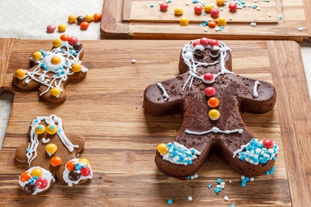 Decorating brown homemade gingerbread man for Christmas on wooden table