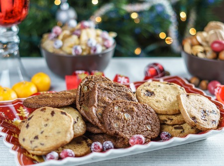 freshly baked chocolate chip cookies on a table with blurred christmas tree backgroundの写真素材