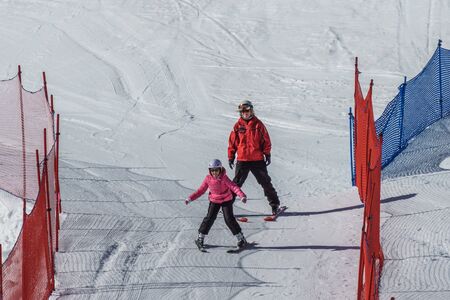 KIMBERLEY, CANADA - MARCH 22, 2019: Mountain Resort view early spring child and ski trainer skiing