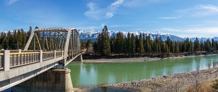 metal bridge over the river with green water in spring with mountains on the background