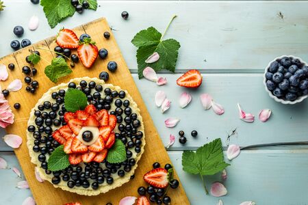 Cake with berries Pie with strawberries and black currants on blue rustic tableの写真素材
