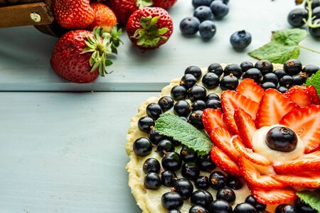 Cake with berries Pie with strawberries and black currants on blue rustic tableの写真素材