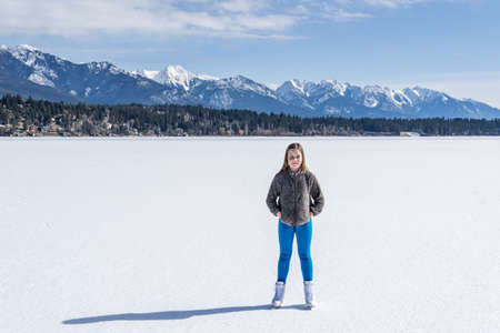 INVERMERE, CANADA - MARCH 17, 2020: girl on frozen Windermere lake and rocky mountains in british columbia canadaのeditorial素材