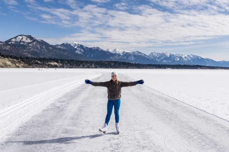 INVERMERE, CANADA - MARCH 17, 2020: girl on frozen Windermere lake and rocky mountains in british columbia canadaのeditorial素材