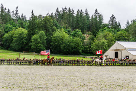 MAPLE RIDGE, CANADA - JULY 5, 2019: horse riders with flags on the field at final day camp show