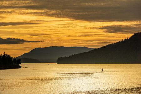 beautiful sunset ocean bay with orange sky mountains and cloudsの写真素材
