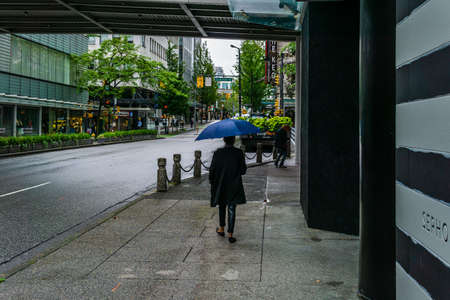 VANCOUVER, CANADA - JUNE 10, 2020: person with umbrella on sidewalk in rainy day.のeditorial素材