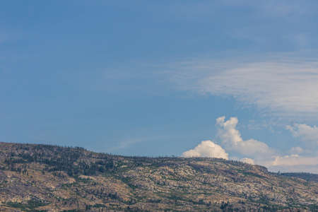 Sky with white clouds above small mountains in okanagan valley Canada.の写真素材