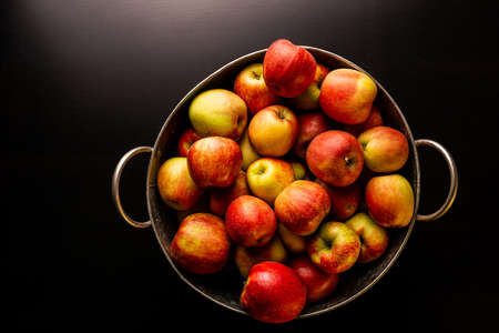 Ripe red apples in washtub on dark background top view