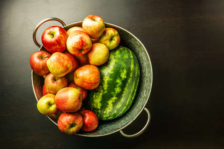 Ripe red apples and watermelon in washtub on dark background top viewの写真素材