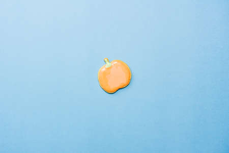 Sweet homemade pumpkin cookie with icing isolated on blue background minimal flat lay composition.の写真素材