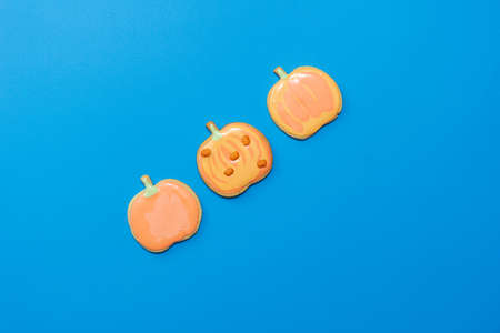 Sweet homemade pumpkin cookie with icing isolated on dark blue background minimal flat lay composition.の写真素材