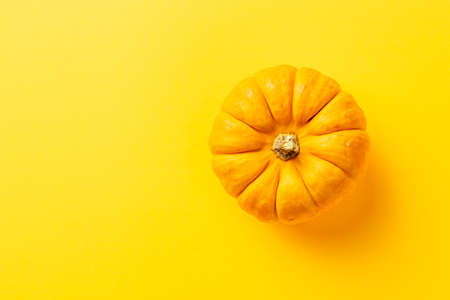 Orange pumpkin isolated over the yellow background top viewの写真素材