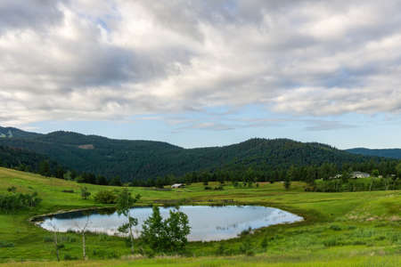 KAMLOOPS, CANADA - AUGUST 4, 2020: Large pond in swampy meadow among rolling hills country side british columbia Canadaのeditorial素材