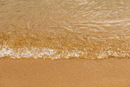 Close-up of a water edge and yellow sand summer beach background with copy space